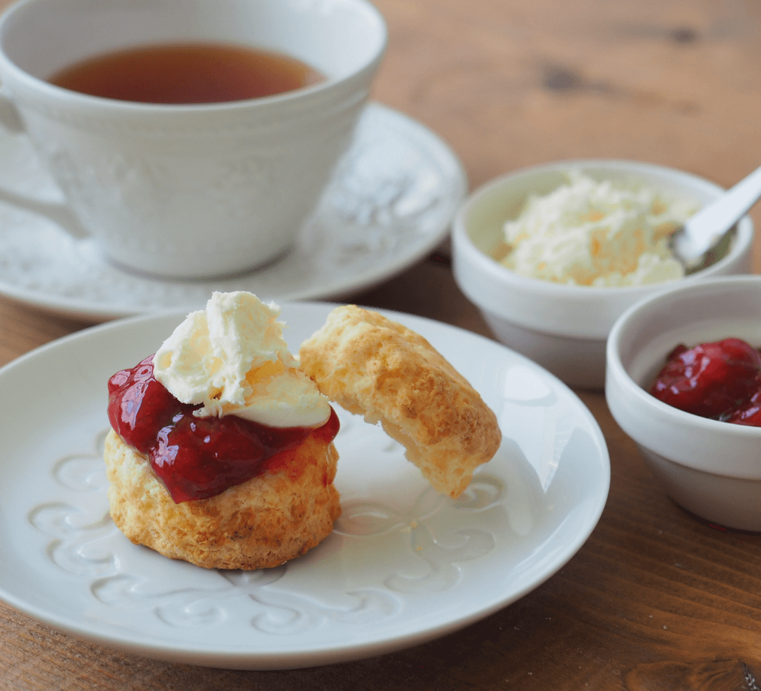 クロテッドクリームとジャムをのせたスコーンの写真