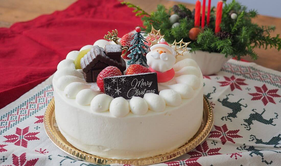 サンタの砂糖菓子やチョコプレートがのったクリスマスケーキの写真